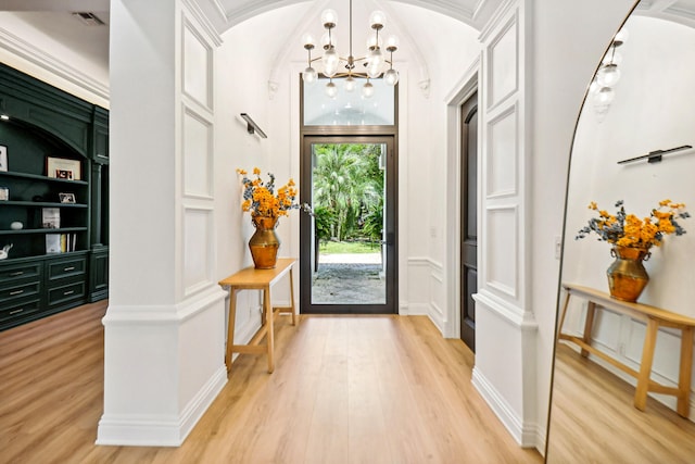 entrance foyer featuring light hardwood / wood-style flooring, a notable chandelier, and crown molding