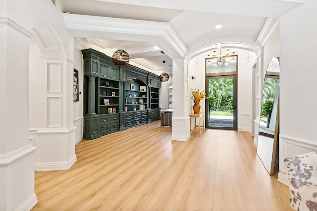 foyer entrance featuring hardwood / wood-style flooring, an inviting chandelier, decorative columns, and crown molding