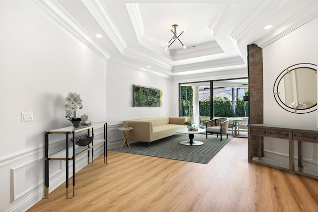 living room with ornamental molding, light hardwood / wood-style floors, and a tray ceiling