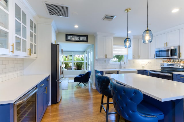 kitchen featuring wine cooler, a center island, hardwood / wood-style flooring, white cabinetry, and stainless steel appliances