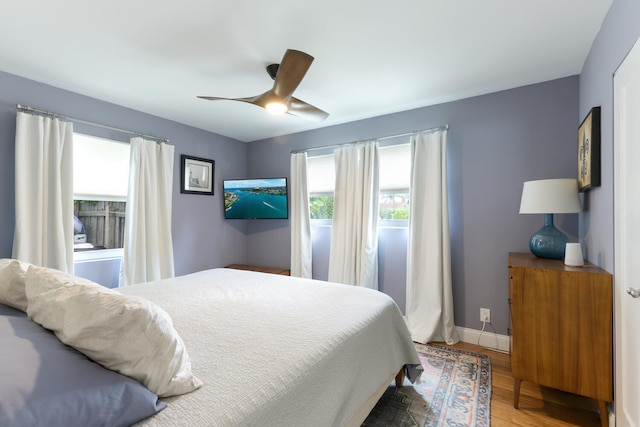 bedroom with wood-type flooring, multiple windows, and ceiling fan