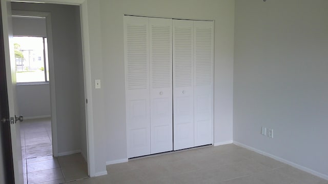 unfurnished bedroom featuring light tile patterned flooring and a closet