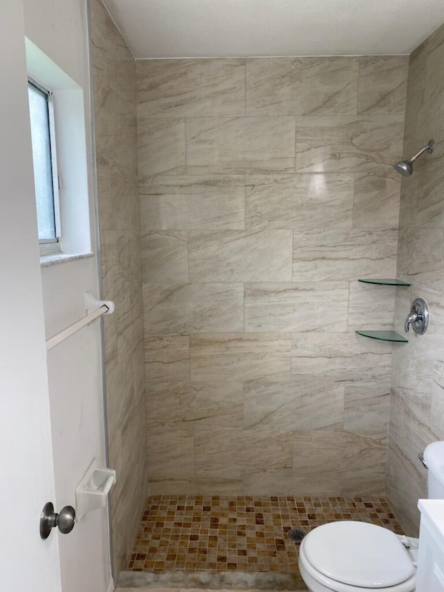 bathroom with a tile shower, vanity, and toilet