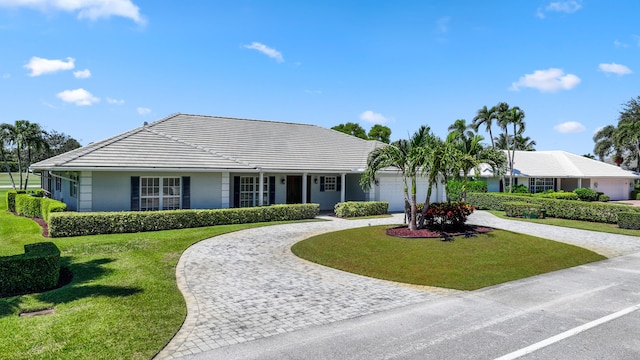 ranch-style house featuring a garage and a front lawn