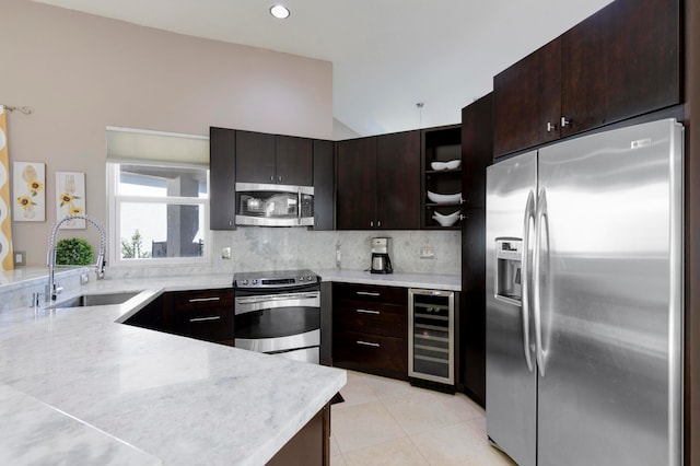 kitchen featuring dark brown cabinetry, wine cooler, sink, appliances with stainless steel finishes, and decorative backsplash