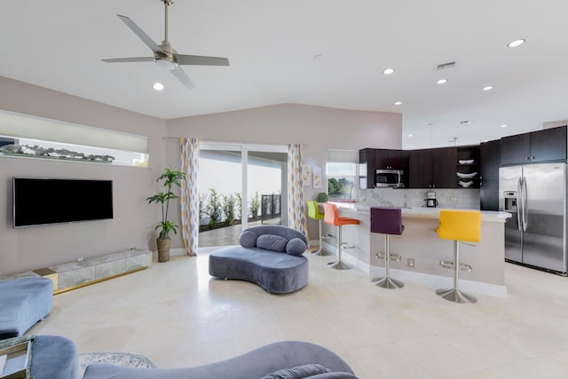 living room featuring light tile patterned floors, vaulted ceiling, and ceiling fan