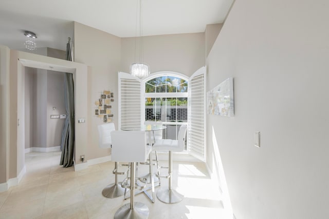 tiled dining area featuring an inviting chandelier and a high ceiling