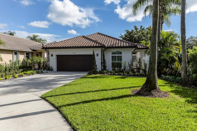 mediterranean / spanish-style home featuring a front lawn and a garage