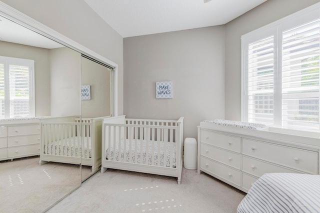 carpeted bedroom with a closet and a crib