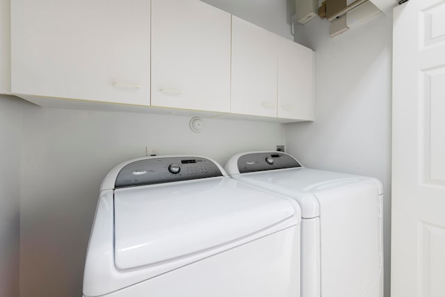 laundry area with separate washer and dryer and cabinets