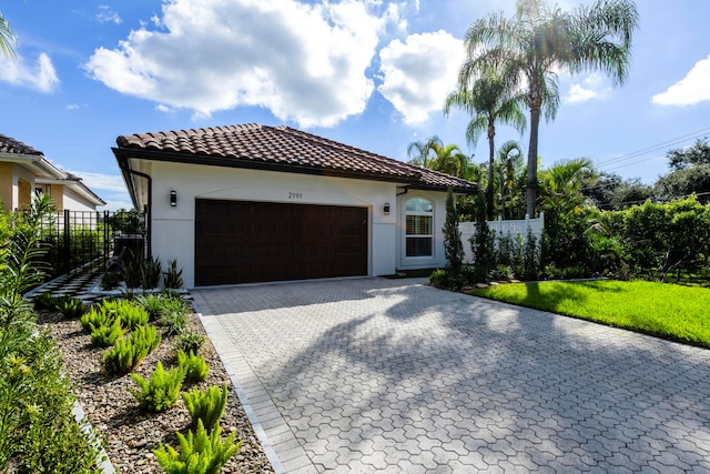 mediterranean / spanish house with a garage and a front lawn