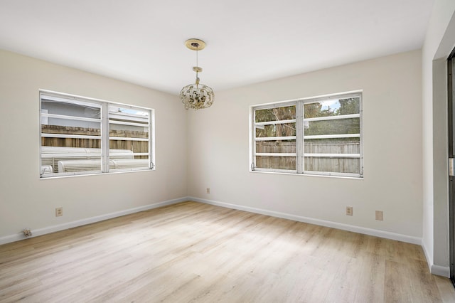 unfurnished room with light hardwood / wood-style floors and a notable chandelier