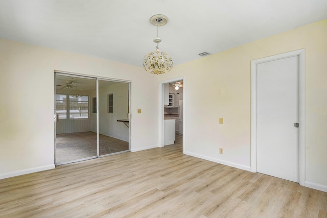 unfurnished bedroom featuring a notable chandelier and light hardwood / wood-style floors