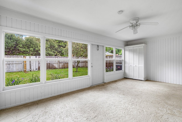 unfurnished sunroom featuring ceiling fan and plenty of natural light