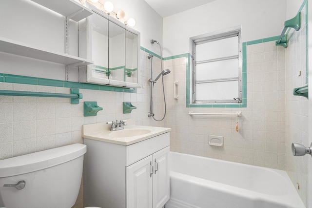 full bathroom featuring tiled shower / bath, vanity, tile walls, and toilet