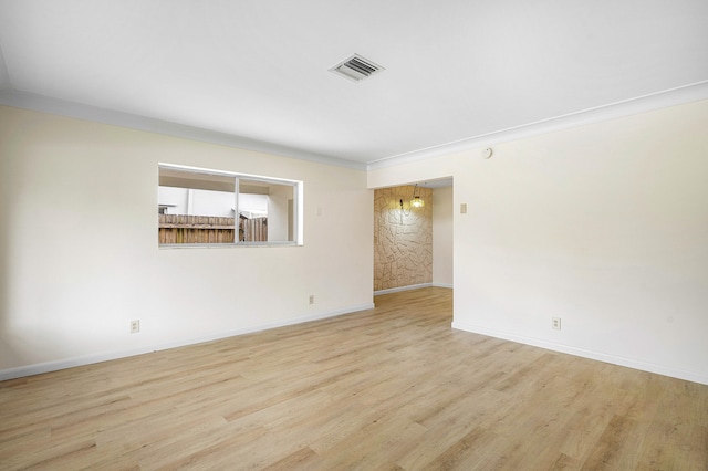 spare room with light wood-type flooring and ornamental molding