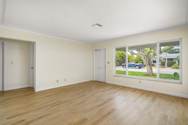 empty room with ornamental molding, plenty of natural light, and light hardwood / wood-style floors