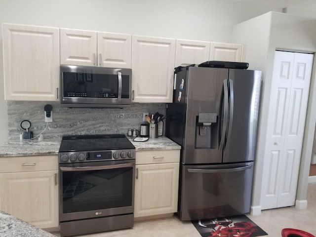 kitchen featuring light stone countertops, appliances with stainless steel finishes, backsplash, and light tile patterned floors