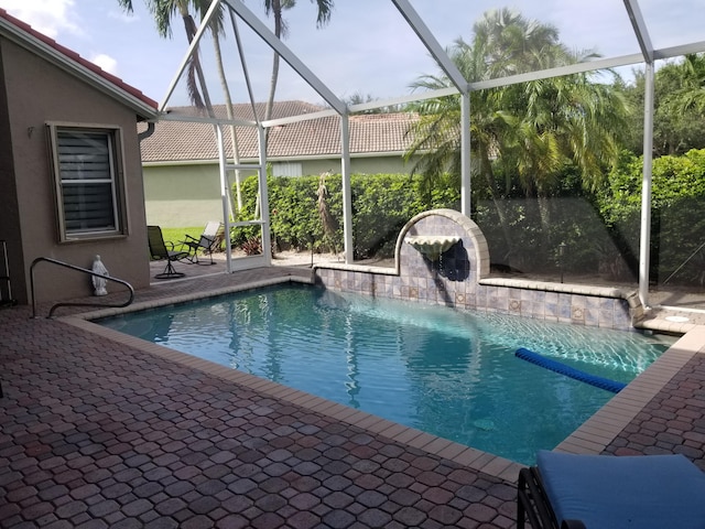 view of pool featuring pool water feature, a patio area, and a lanai