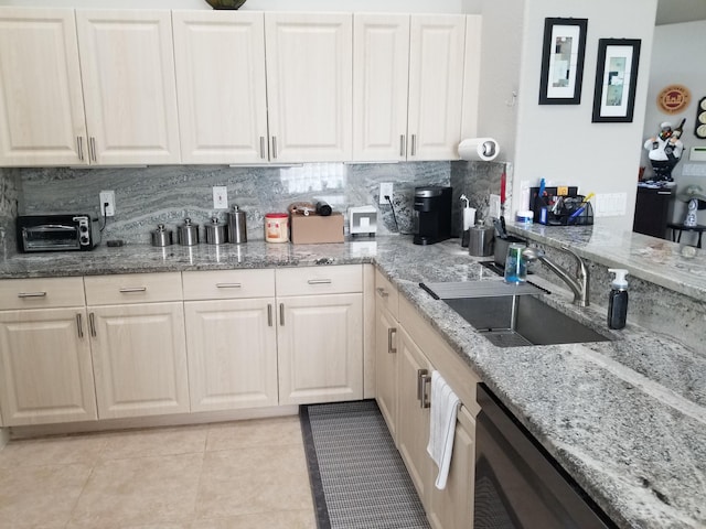 kitchen featuring light stone counters, stainless steel dishwasher, tasteful backsplash, sink, and light tile patterned floors