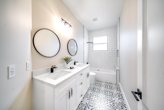 full bathroom featuring tiled shower / bath, vanity, toilet, and tile patterned floors