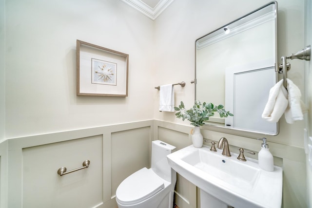 bathroom with crown molding, toilet, and sink