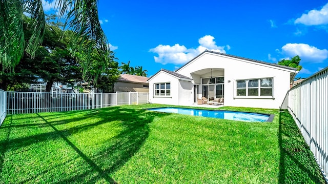 back of house with a yard and a fenced in pool