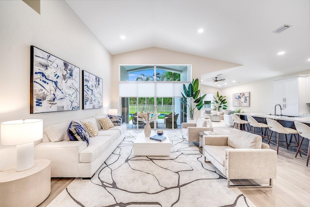 living room with vaulted ceiling, ceiling fan, light hardwood / wood-style flooring, and sink