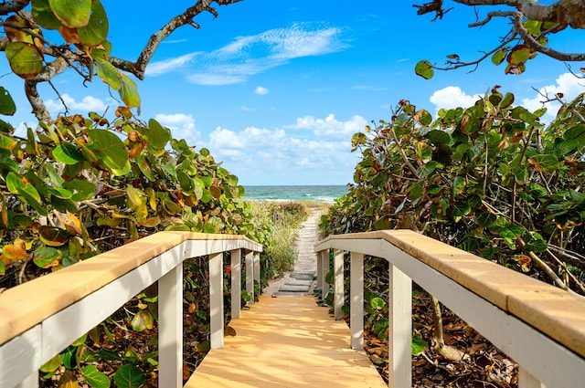 view of property's community with a water view and a beach view