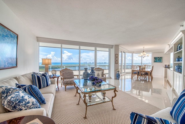 living room featuring expansive windows, a textured ceiling, a chandelier, and a water view