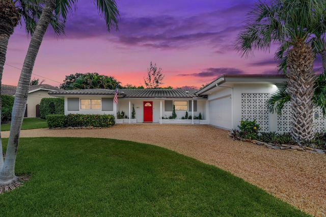 single story home featuring a garage and a yard