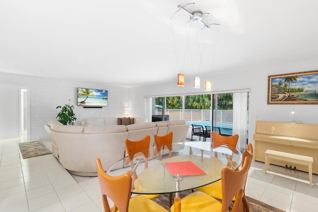 tiled dining space featuring ceiling fan and brick wall