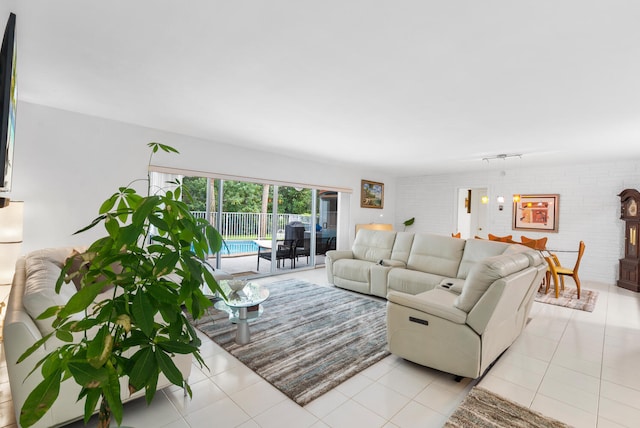 living room featuring rail lighting, light tile patterned floors, and brick wall