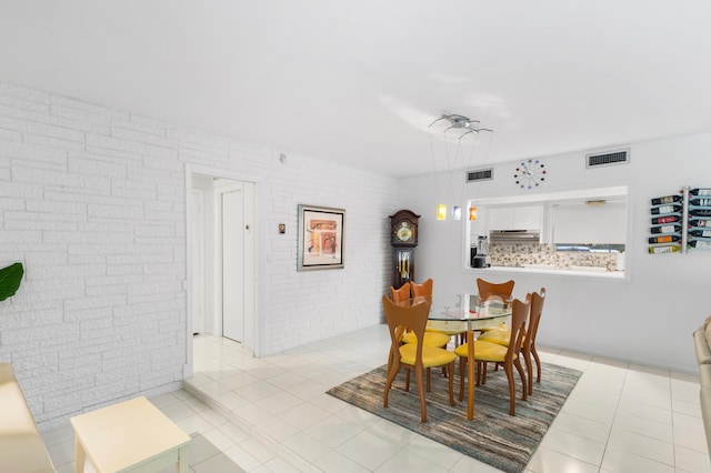 dining area featuring light tile patterned floors and brick wall