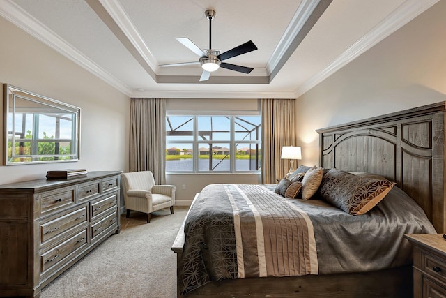 carpeted bedroom with a tray ceiling, multiple windows, ceiling fan, and crown molding