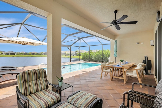 view of patio / terrace featuring glass enclosure, a water view, and ceiling fan