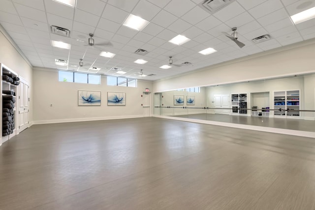 workout area featuring ceiling fan and a paneled ceiling