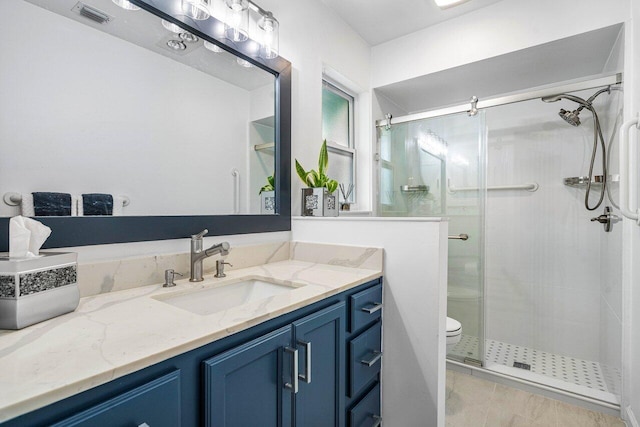 bathroom featuring tile patterned flooring, vanity, toilet, and walk in shower