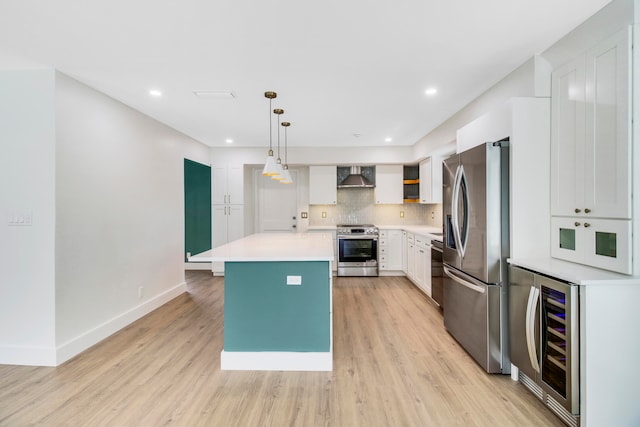 kitchen with beverage cooler, decorative light fixtures, wall chimney range hood, stainless steel appliances, and a center island