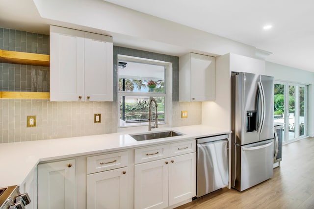 kitchen with plenty of natural light, sink, stainless steel appliances, and white cabinets