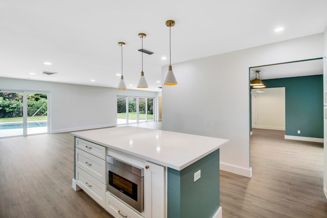 kitchen with decorative light fixtures, stainless steel microwave, and a healthy amount of sunlight