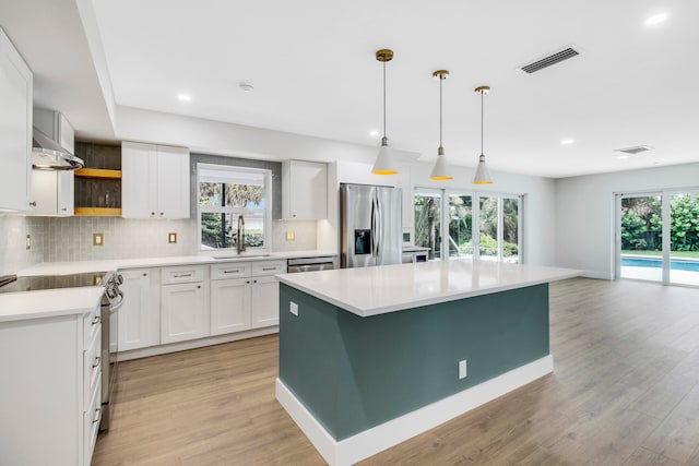 kitchen featuring sink, white cabinetry, appliances with stainless steel finishes, a center island, and light hardwood / wood-style floors