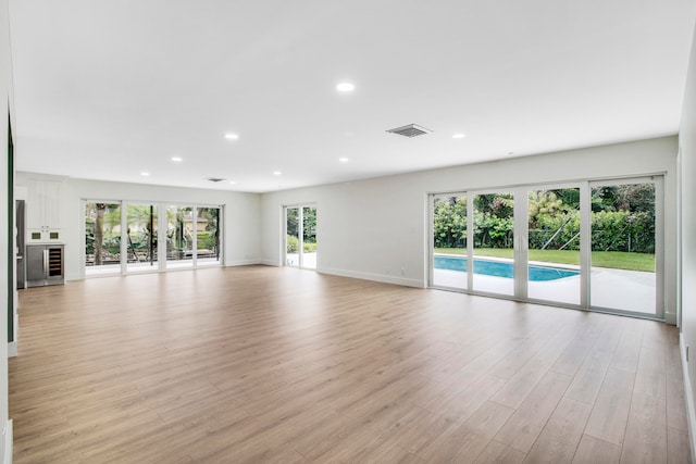 unfurnished living room with light hardwood / wood-style floors and beverage cooler