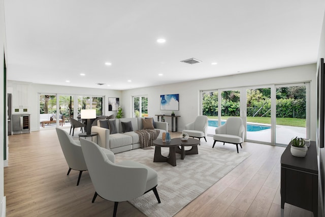 living room with french doors, light hardwood / wood-style floors, and a healthy amount of sunlight