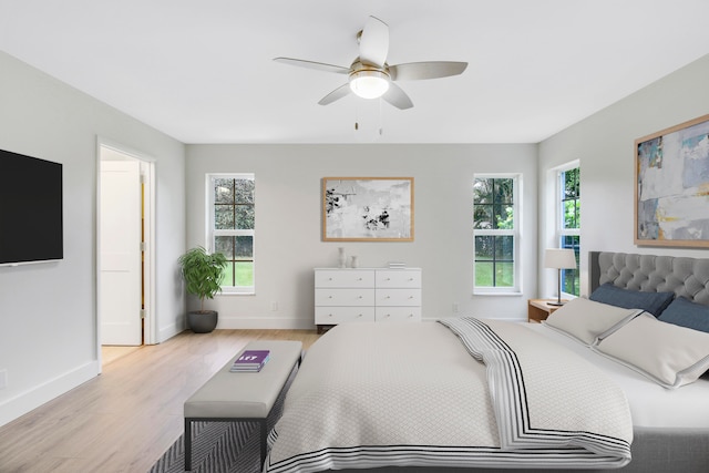 bedroom featuring light wood-type flooring, multiple windows, and ceiling fan