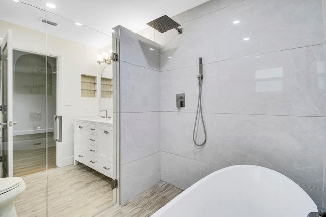 full bathroom featuring vanity, separate shower and tub, wood-type flooring, tile walls, and toilet