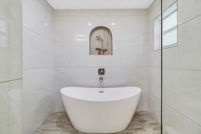 bathroom featuring a tub to relax in and tile walls