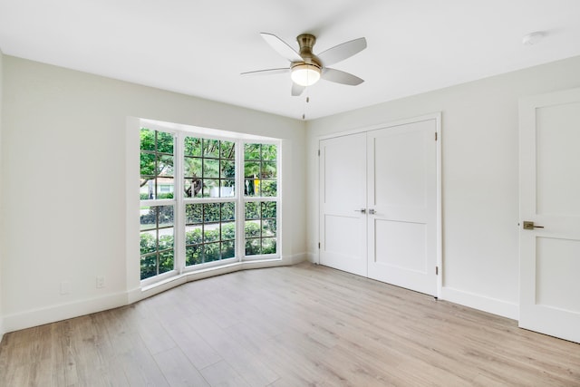 unfurnished bedroom featuring light wood-type flooring, ceiling fan, and a closet