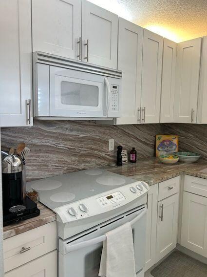 kitchen featuring white appliances, tasteful backsplash, and white cabinets