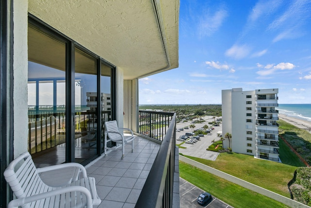 balcony with a water view and a view of the beach